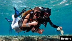 An assistant escorts a model as she dives to a location of an underwater photo shoot in the Red Sea in the resort city of Eilat, Oct. 23, 2013.