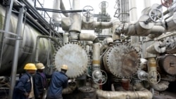 FILE - Workers try to tie a pipe at an oil refinery in Port Harcourt, Rivers State, Nigeria, Sept. 16, 2015.