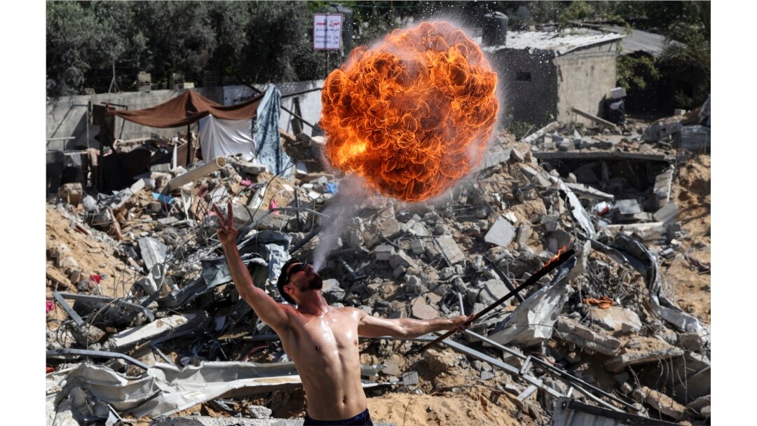 Anggota tim olahraga Bar Woolf Gaza tampil dengan api di atas reruntuhan bangunan yang hancur akibat serangan udara Israel baru-baru ini, di Beit Lahia, pada 26 Mei 2021. (Foto: AFP)