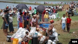 ក្រុម​ជន​រ៉ូហ៊ីងយ៉ា ជួប​ជុំ​គ្នា​ដោយ​មាន​បង្វិច​អីវ៉ាន់​របស់​ពួក​គេ​នៅ​ជាមួយ​ផង នៅ​ខណៈ​មាន​អគ្គិភ័យ​នៅ​ក្នុង​​ជំរំ​ នៅក្រុង Sittwe រដ្ឋ Rakhine ភាគខាង​លិច​ប្រទេស​ភូមា កាល​ពី​ខែ​ឧសភា។