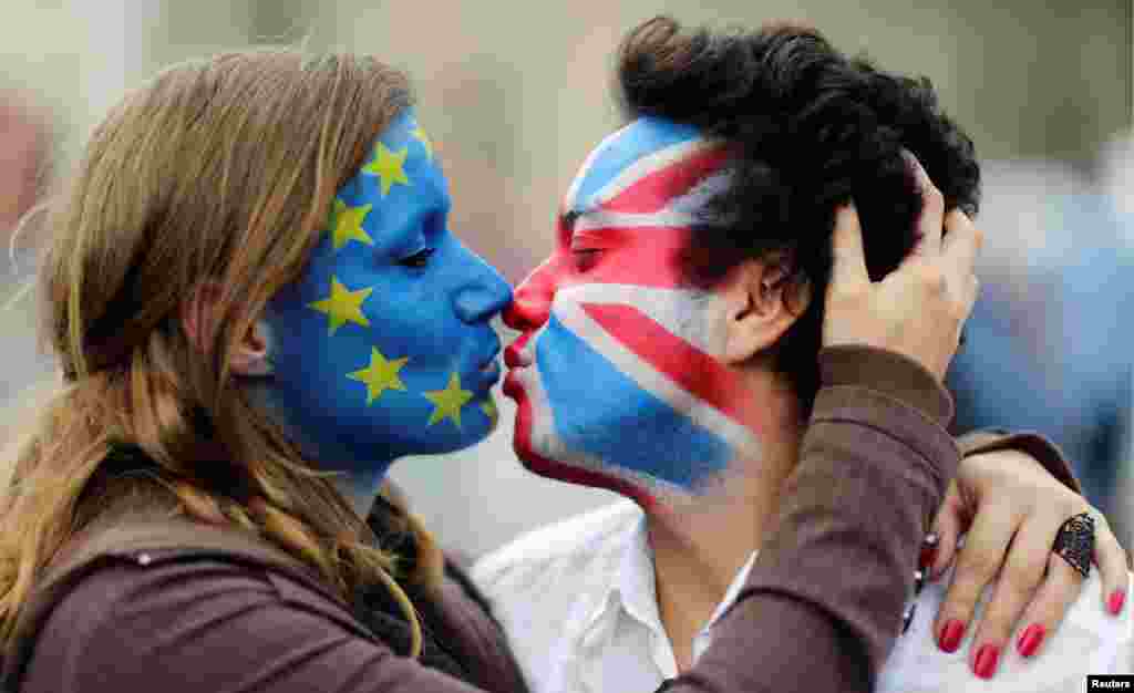 Two activists with the EU flag and Union Jack painted on their faces kiss each other in front of Brandenburg Gate in Berlin, Germany, to protest against the British exit from the European Union.