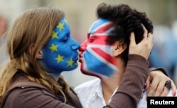 Two activists with the EU flag and Union Jack painted on their faces kiss each other in front of Brandenburg Gate to protest against the British exit from the European Union, in Berlin, Germany, June 19, 2016.