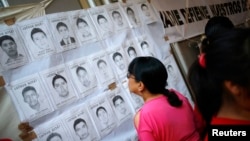 A woman looks at pictures of the 43 missing students from the Ayotzinapa teachers' training college during a demonstration to demand justice for them, outside of the National Human Rights Commission, (CNDH) in Mexico City, November 6, 2014. The students w