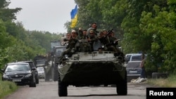Ukrainian soldiers ride atop an Armored Personnel Carrier (APC) near the site where pro-Russia rebels killed Ukrainian servicemen in the outskirts of the eastern Ukrainian town of Volnovakha, south of Donetsk May 22, 2014.