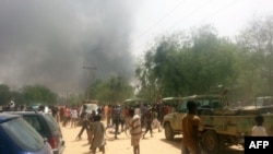 FILE - People look at smoke rising after suspected Boko Haram Islamists attack a military base in the northeast Nigerian city of Maiduguri. 