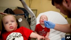 Kilian Daugherty, 1, gets his nose swabbed for the flu by emergency department technician Jake Weatherford as his sister Madison, left, waits to be examined as well for flu symptoms at Upson Regional Medical Center in Thomaston, Georgia, Feb. 9, 2018.