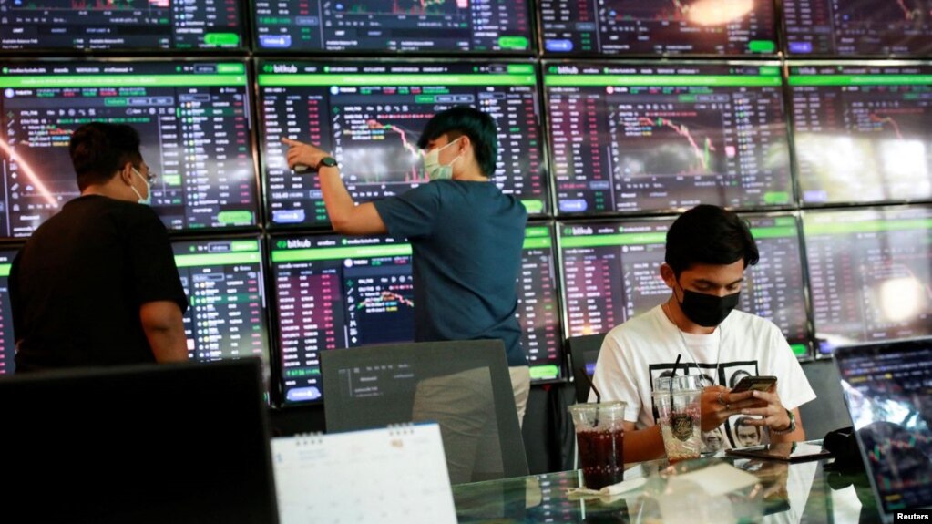 People pass their time at a cafe which has dozens of screens showing the latest trends and prices on various cryptocurrencies for their crypto investors' customers in Nakhon Ratchasima, Thailand January 21, 2022. REUTERS/Soe Zeya Tun