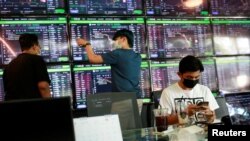 People pass their time at a cafe which has dozens of screens showing the latest trends and prices on various cryptocurrencies for their crypto investors' customers in Nakhon Ratchasima, Thailand January 21, 2022. REUTERS/Soe Zeya Tun