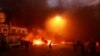 Para demonstran membakar ban-ban dan gedung dekat stasiun TV pemerintah, sementara pasukan keamanan menembakkan peluru tajam dan gas air mata dalam protes rusuh di Baghdad, Senin (4/11). 