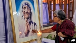 An Indian Catholic woman offers prayers as she touches a portrait of Mother Teresa on her 17th death anniversary at the Missionaries of Charity in Kolkata, in 2014. Mother Teresa is to be named a saint by the Roman Catholic Church.