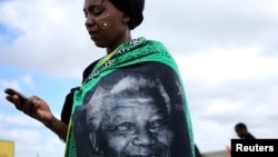 A woman, draped in a cloth with an image of former South African President Nelson Mandela, uses a mobile phone during Mandela's funeral at his ancestral village of Qunu in Eastern Cape province, south of Johannesburg, Dec. 15, 2013.