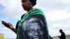 A woman, draped in a cloth with an image of former South African President Nelson Mandela, uses a mobile phone during Mandela's funeral at his ancestral village of Qunu in Eastern Cape province, south of Johannesburg, Dec. 15, 2013.