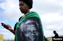 A woman, draped in a cloth with an image of former South African President Nelson Mandela, uses a mobile phone during Mandela's funeral at his ancestral village of Qunu in Eastern Cape province, south of Johannesburg, Dec. 15, 2013.