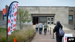 Les gens entrent dans un auditorium de la Morgan State University pour voter, le deuxième jour du vote anticipé de la course présidentielle américaine, à Baltimore, le 27 octobre 2020.