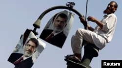 A member of the Muslim Brotherhood and supporter of ousted Egyptian President Mohamed Morsi places posters of Morsi on a lamp post, during a protest in front of the courthouse and the Attorney General's office, in Cairo, July 22, 2013.