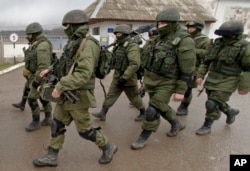 FILE - Troops, believed to be Russian special forces in uniforms without insignia, march outside a Ukrainian military base in Perevalne, Crimea, March 20, 2014.