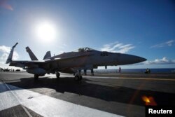 FILE - A F/A 18E Super Hornet on the USS Ronald Reagan taxis on deck before take off.