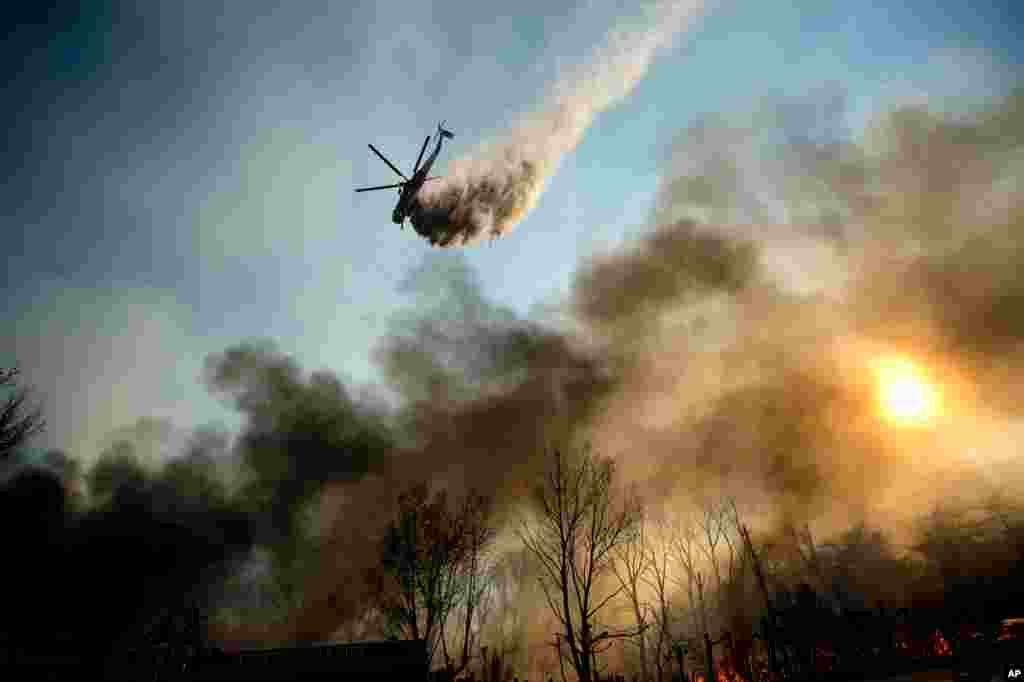یک هلیکوپتر در حال پاشیدن آب روی آتش در منطقۀ کن بروک ایالت کالیفورنیا.
