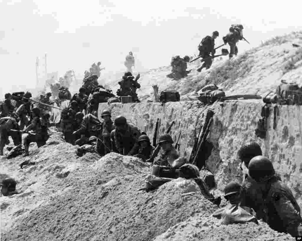 American troops move over the crest of a hill to the interior of Northern France, June 6, 1944. (AP Photo)