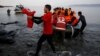 A Red Cross volunteer carries a Syrian refugee baby off an overcrowded raft at a beach on the Greek island of Lesbos Nov. 16, 2015. 