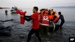 A Red Cross volunteer carries a Syrian refugee baby off an overcrowded raft at a beach on the Greek island of Lesbos Nov. 16, 2015.