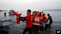 A Red Cross volunteer carries a Syrian refugee baby off an overcrowded raft at a beach on the Greek island of Lesbos Nov. 16, 2015. 