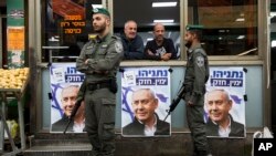 Israeli border police officers stand guard next to posters depicting Israeli Prime Minister Benjamin Netanyahu at the Ha'tikva market in Tel Aviv, Israel, April 2, 2019. 