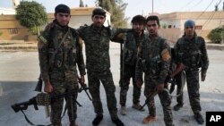 FILE - In this July 22, 2017, photo, Arab and Kurdish fighters with the U.S.-backed Syrian Democratic Forces (SDF), pose for a picture as they prepare to move to the front line to battle against the Islamic State militants, in Raqqa, northeast Syria.