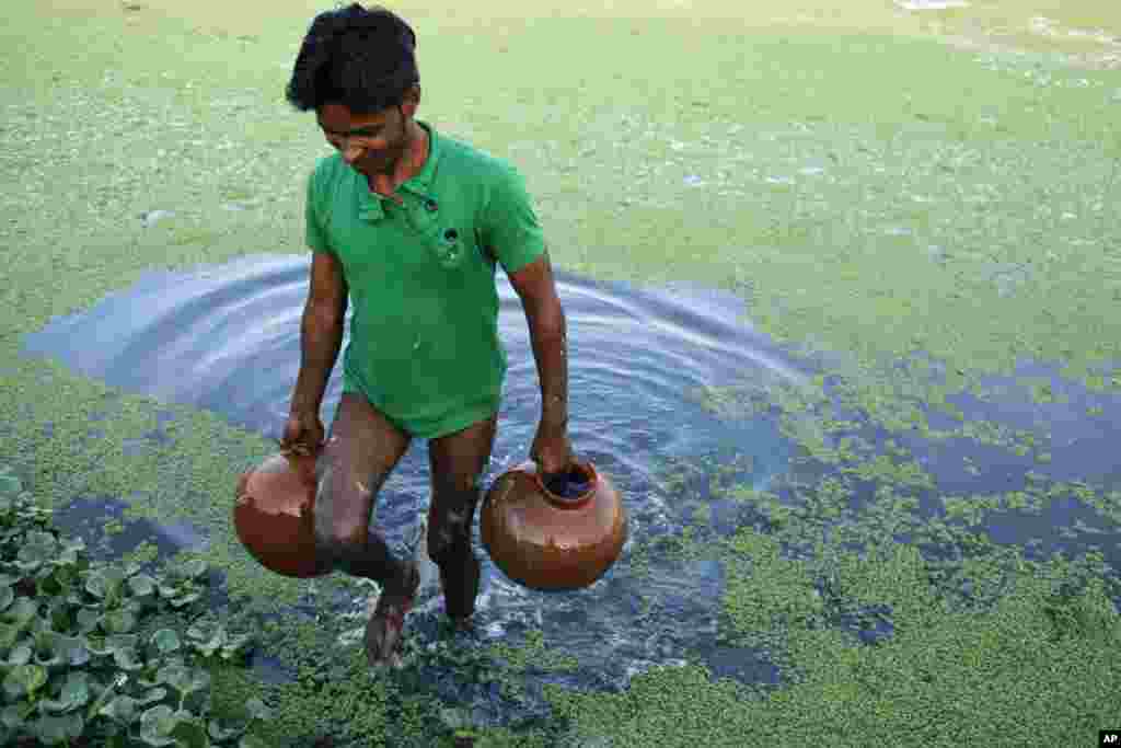 An Indian farmer fetches water from a pond to irrigate his cucumber plants on the eve of World Water Day in Allahabad, March 21, 2013.&nbsp; The U.N. estimates that more than one in six people worldwide do not have access to 20-50 liters of safe freshwater a day to ensure their basic needs.