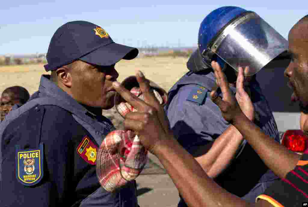 Police attempt to stop mine workers from marching towards the mine before a memorial service, near the Lonmin's platinum mine in Marikana, South Africa, August 16, 2013.