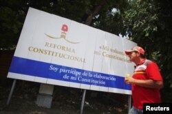 A Cuban walks past a billboard promoting the public political discussion to revamp a Cold War-era constitution in Havana, Aug. 10, 2018.