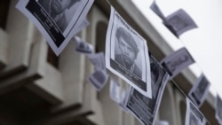 Fotos de personas que fueron desaparecidas por la fuerza cuelgan frente al edificio de la Corte Suprema de Guatemala durante una audiencia de caso de genocidio.