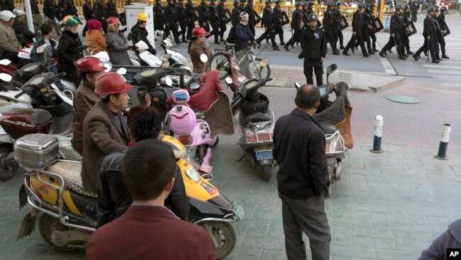 2017年11月5日，中部新疆地区的喀什市居民观看一队保安人员。