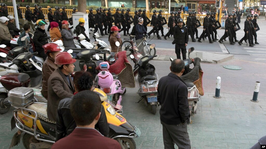 2017年11月5日，中部新疆地区的喀什市，居民观看一队保安人员。