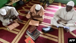 Les musulmans lisent un Coran après une prière du vendredi dans une mosquée d'Abidjan pendant le mois sacré du Ramadan, le 18 mai 2018 