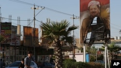 A burned poster of Massoud Barzani, the President of Iraq's autonomous Kurdish region, is displayed in front of the abandoned building of Kurdish security forces in Kirkuk, Iraq, Oct. 19, 2017.