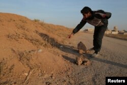 A resident points to what he believes is a land mine in the village of al-Heesha in Raqqa district of Syria after it was captured from the Islamic State, Nov. 15, 2016.