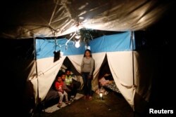 FILE - Veronica Dircio, 34, a housewife, stands with her sons in front of a tent in a neighbor's backyard after an earthquake in San Juan Pilcaya, at the epicenter zone, Mexico, Sept. 28, 2017.