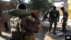 FILE - U.S.-backed Syrian Democratic Forces fighters, prepare to fire a mortar shell, at one of the front lines, in Raqqa city, northeast Syria, July 27, 2017.