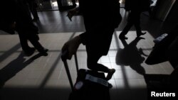 Passengers cast shadows as they walk along a terminal at Los Angeles International Airport in Los Angeles, California, March 4, 2013.