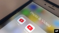 The YouTube app and YouTube Kids app are displayed on an iPhone in New York, April 25, 2018. YouTube is overhauling its kid-focused video app to give parents the option of letting humans, not computer algorithms, select what shows their children can watch