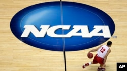 Pebasket Traevon Jackson menggiring bola melewati logo NCAA atau Asosiasi Atletik Perguruan Tinggi AS, dalam laga bola basket di Anaheim, California, 26 Maret 2014. 