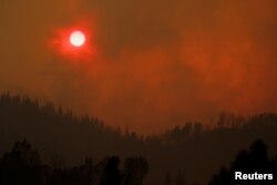 The setting sun is turned red by the smoke from the Carr Fire burning in the hills west of Redding, Calif., July 27, 2018.