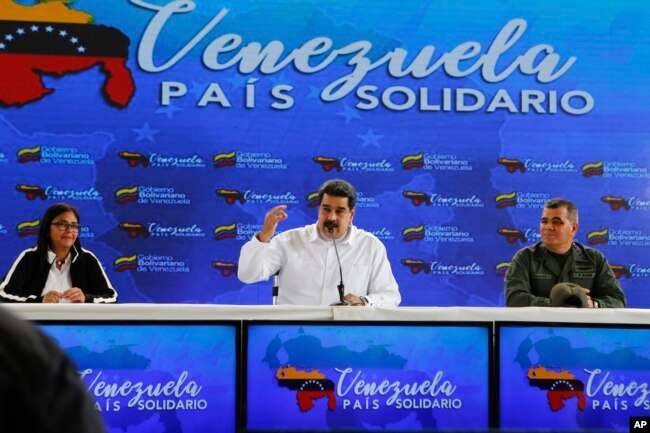 El presidente de Venezuela, Nicolás Maduro, en el centro, habla, mientras lo acompaña el vicepresidente venezolano, Delcy Rodríguez, a la izquierda, y el ministro de Defensa, Vladimir Padrino, a la derecha, durante una reunión con ciudadanos colombianos que residen en Venezuela. Caracas, 26 de septiembre de 2018. Foto de la oficina de prensa del Palacio de Miraflores via AP.