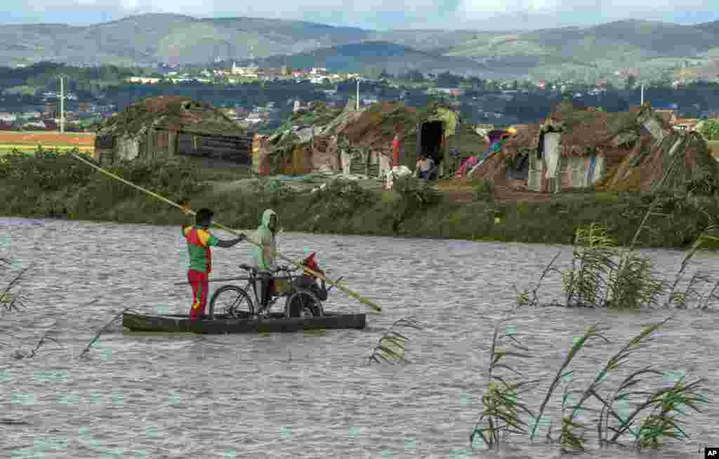 Residents cross flooded fields in Madagascar&#39;s capital Antananarivo. Officials say the death toll from Cyclone Enawo has risen to at least five and about 10,000 people have left their homes because of storm damage.