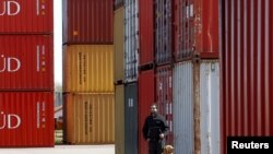 An Argentina tax official and his sniffer dog are shown by containers loaded with grains at the port in Argentina. (File)