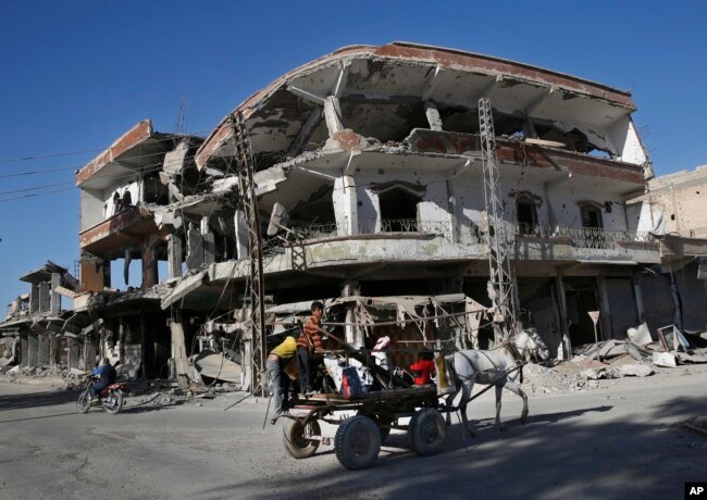 FILE - The remains of buildings line a street that was damaged the previous summer during fighting between U.S.-backed Syrian Democratic Forces fighters and Islamic State militants, in Raqqa, Syria, April 5, 2018.