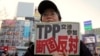 FILE - A protester holds a sign reading "We oppose Japan to join the TPP negotiation talks" during a rally against the Trans-Pacific Partnership in Tokyo. 