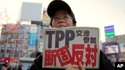 FILE - A protester holds a sign reading "We oppose Japan to join the TPP negotiation talks" during a rally against the Trans-Pacific Partnership in Tokyo. 