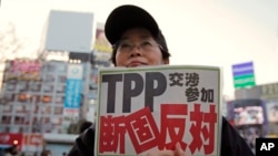 FILE - A protester holds a sign reading "We oppose Japan to join the TPP negotiation talks" during a rally against the Trans-Pacific Partnership in Tokyo.